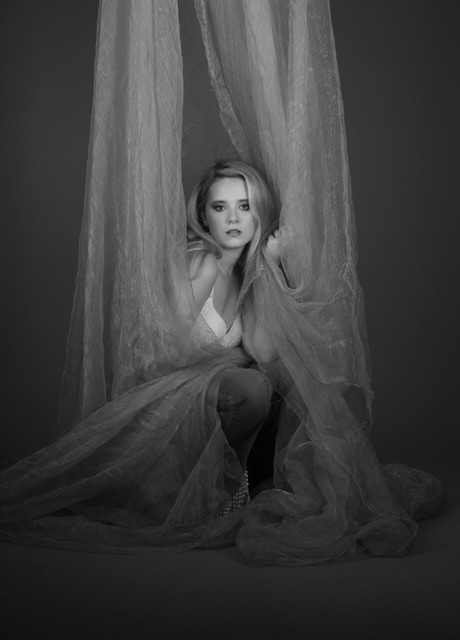 Monochrome seated portrait framed by fabric